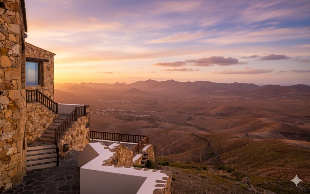 Vista aérea del Mirador de Morro Velosa en Fuerteventura al atardecer, mostrando la arquitectura de César Manrique integrada en el paisaje montañoso ocre de la isla.