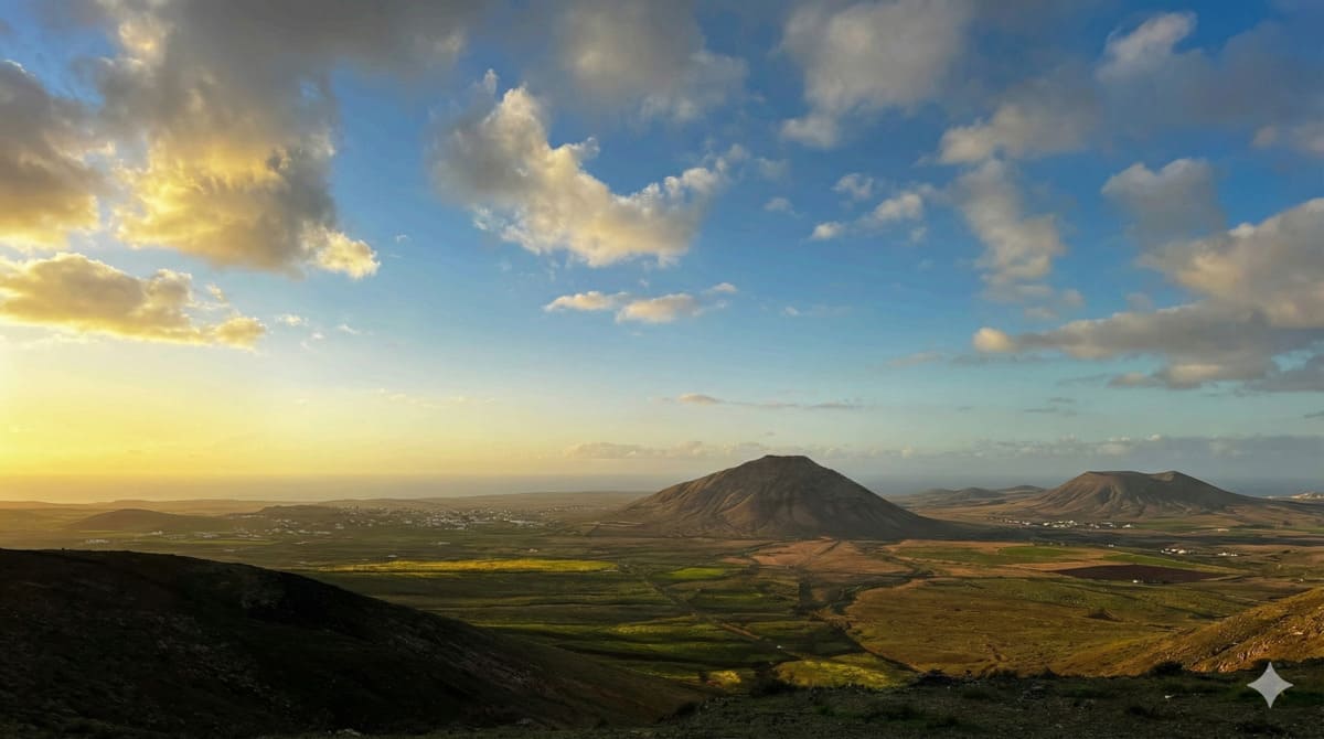 Vista panorámica de Vallebrón al atardecer, con valle verde, montañas y cielo con nubes en Fuerteventura.