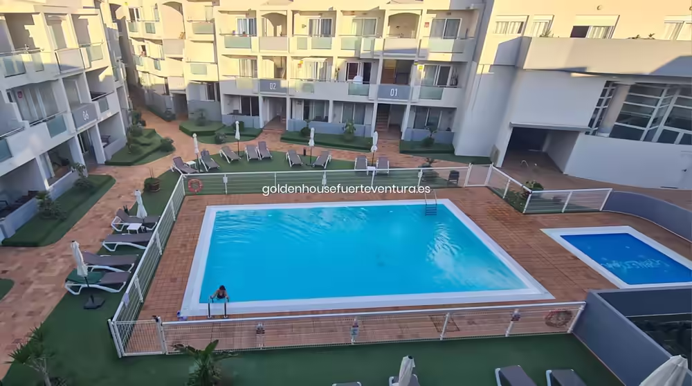 Amplia piscina central con zonas de descanso y balcones del complejo.