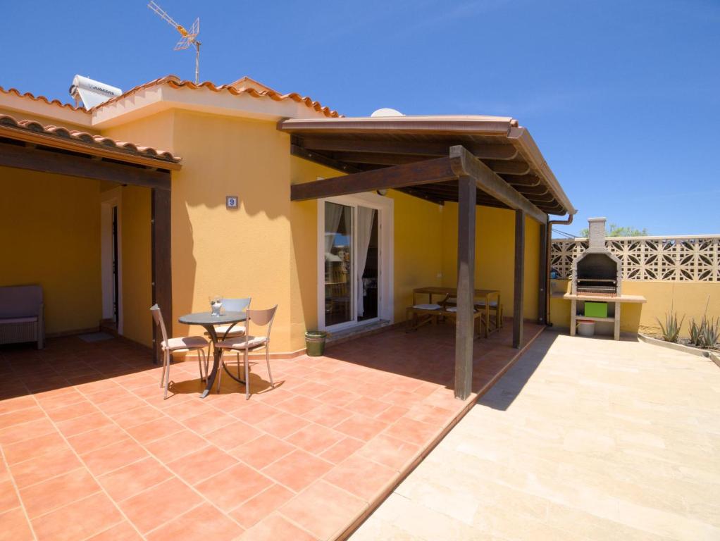 Terraza exterior con mesa de comedor y barbacoa de obra bajo el sol.