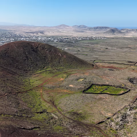 Vista cenital de dron enfocando directamente el fondo del cráter del volcán Calderón Hondo, mostrando los tonos rojizos, amarillos y ocres de la roca volcánica.
