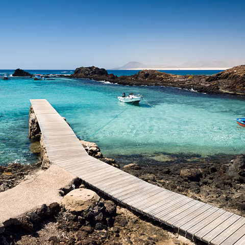 Panorámica de las lagunas de aguas turquesas en El Puertito del Islote de Lobos, mostrando la calma del mar y las rocas volcánicas que las rodean.