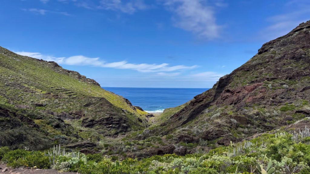 Sendero entre montañas verdes con vistas al océano Atlántico en las Islas Canarias.