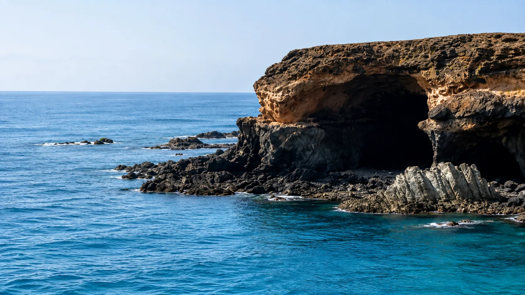 Vista panorámica de las Cuevas de Ajuy en Fuerteventura, con impresionantes acantilados volcánicos, el océano Atlántico y una de las formaciones geológicas más antiguas de Canarias.