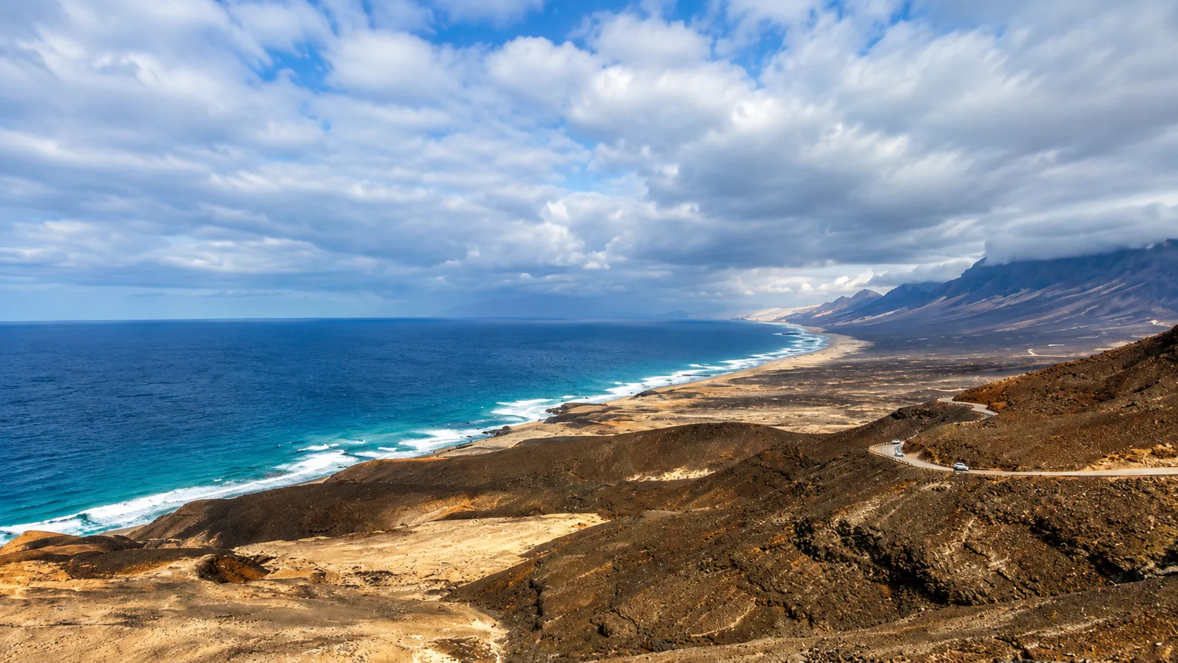Vista panorámica de la playa de Cofete desde el mirador, con la península de Jandía, el océano Atlántico y las montañas del Parque Natural de Jandía en Fuerteventura.