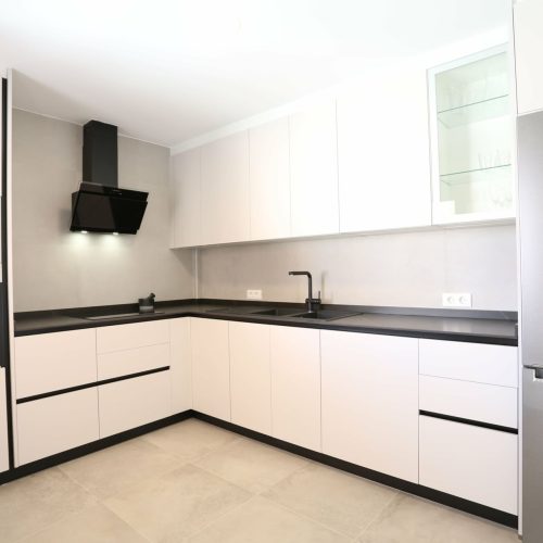 Cocina equipada con muebles blancos y encimera negra en la Villa Shakespeare, Fuerteventura