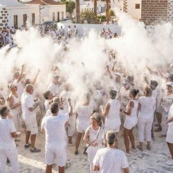 Multitud vestida de blanco celebrando la Fiesta de los Polvos Talco en Tetir, con una nube de talco en la plaza.