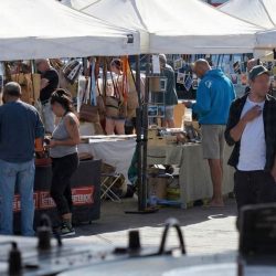 Puestos de artesanía en el Mercadillo de Lajares, con carpas blancas y visitantes comprando productos locales en la plaza.
