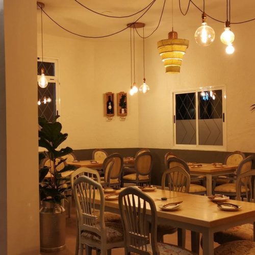 Mesas de madera y lámparas colgantes en el salón principal de La Puipana