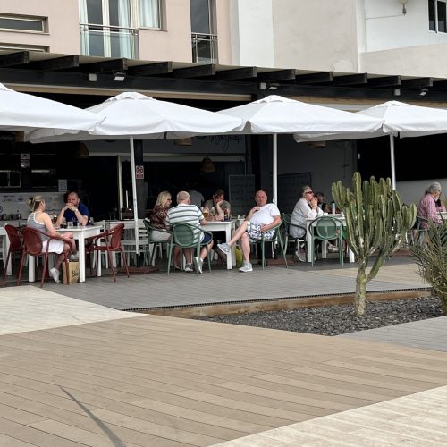 Terraza con sombrillas y clientes en El Rinconcito de Doña Juanita, junto al paseo marítimo de Fuerteventura