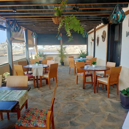 Amplia y luminosa terraza cubierta del restaurante Aroma de Sal, con mesas de madera listas para los comensales y decoración marinera.