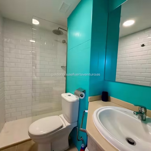 Baño con azulejos blancos y pared color turquesa en Fuerteventura.