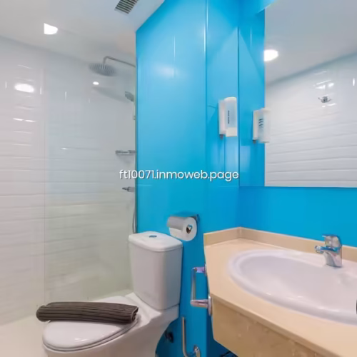 Baño con revestimiento azul, mampara de cristal y plato de ducha