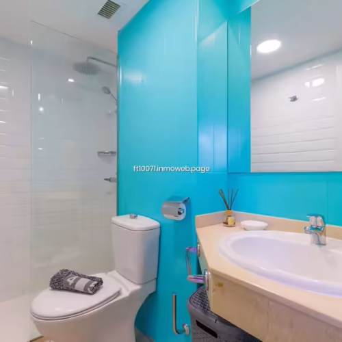 Cuarto de baño con azulejos azul turquesa, lavabo encastrado y ducha con mampara.