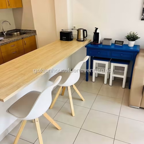 Barra de madera con sillas blancas y cafetera en Fuerteventura.