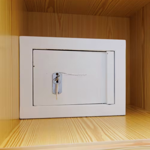 Caja fuerte blanca con llave instalada dentro de un estante de madera.