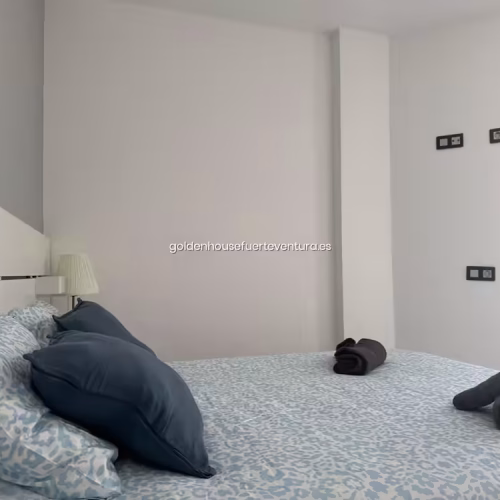 Cama de matrimonio con sábanas en tonos azul claro y almohadas a juego.