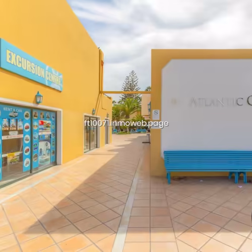Entrada a oficina de servicios turísticos con banco azul en el exterior.