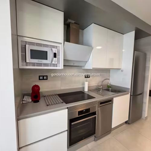 Cocina moderna con microondas, horno y cafetera roja en Fuerteventura.