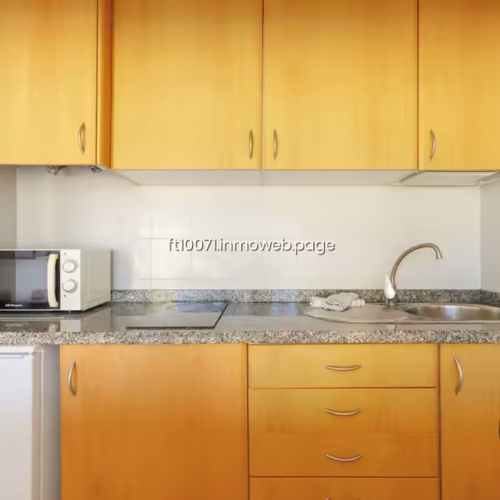 Cocina funcional con microondas, vitrocerámica y nevera bajo encimera