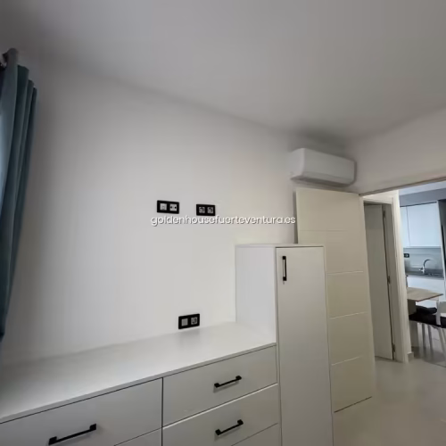 Cómoda blanca con cajones y unidad de aire acondicionado en la habitación.