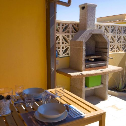 Primer plano de mesa exterior preparada junto a una barbacoa de piedra.