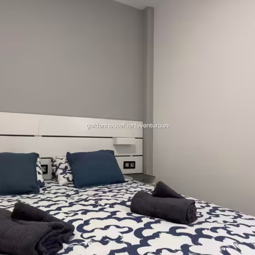 Cabecero de listones blancos con luces de lectura integradas y almohadones azules.