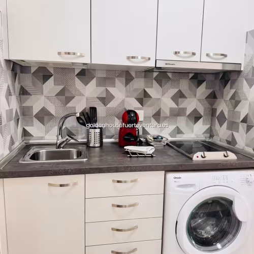 Frontal de cocina con salpicadero geométrico, cafetera roja y menaje en Fuerteventura