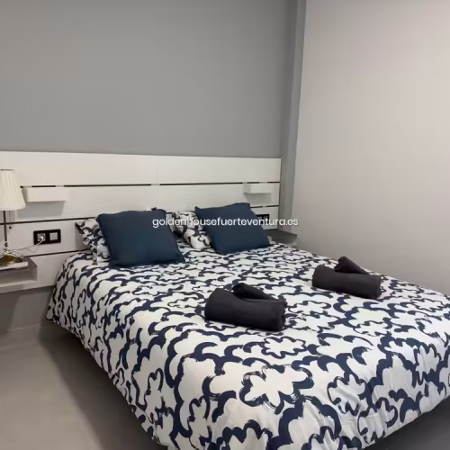 Cabecero de madera blanca con mesitas de noche integradas y lámpara de lectura.