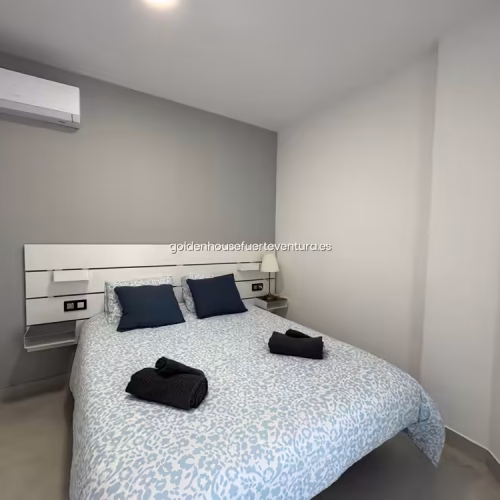 Habitación con cama doble, cabecero de diseño y aire acondicionado sobre la cama.