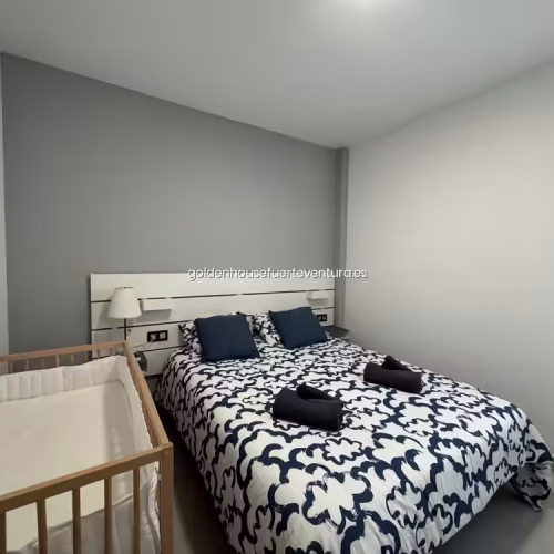 Dormitorio con cama doble preparada con toallas y cuna de madera al lado.