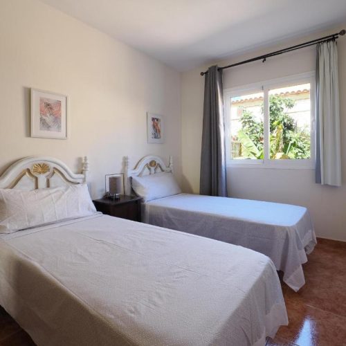 Habitación luminosa con dos camas individuales y ventana con vistas al jardín.