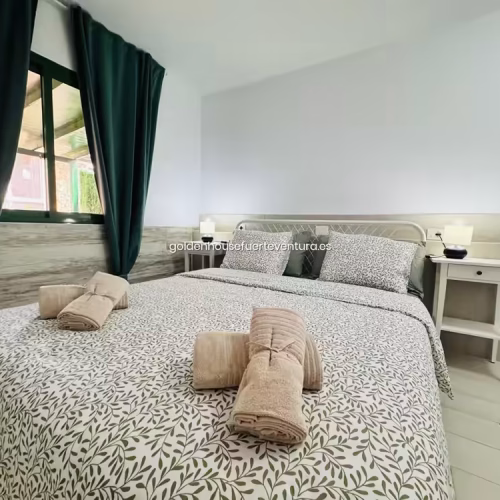 Cama doble con textiles de hojas y cuna blanca de madera en Fuerteventura