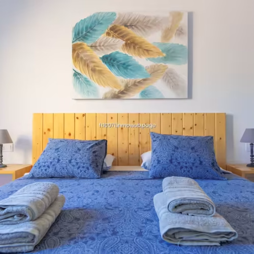 Cama doble con ropa de cama azul y cabecero de listones de madera natural.