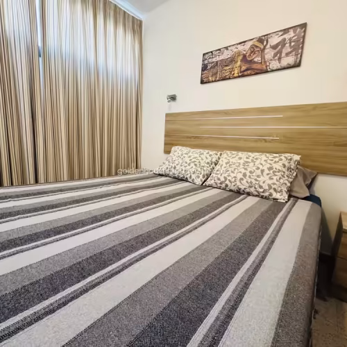 Habitación con cama doble, cabecero de madera, mesilla de noche y cuadro decorativo.