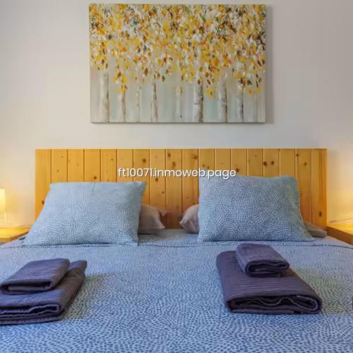Cabecero de madera y cama doble con toallas de cortesía en el dormitorio