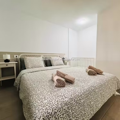 Cama doble con textiles de hojas y cuna blanca de madera en Fuerteventura