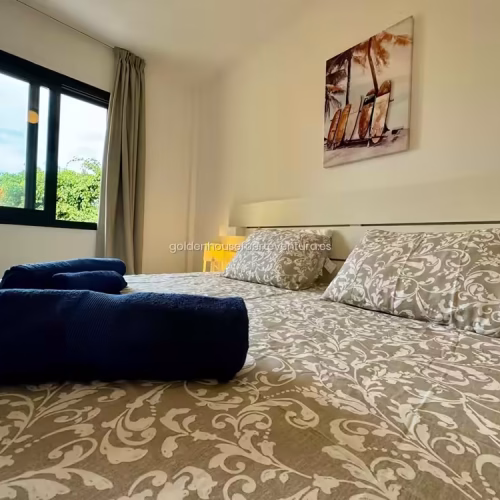 Dormitorio con dos camas juntas y cuadro de tablas de surf en Fuerteventura.