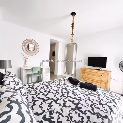 Habitación con ventilador de pie negro junto a cómoda de madera y espejo.