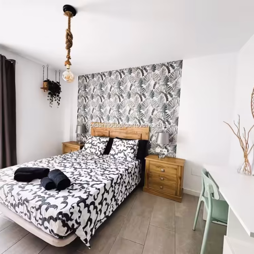 Dormitorio luminoso con cortinas grises, cama doble y papel pintado botánico.