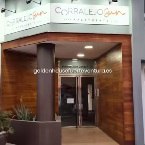 Fachada exterior con letrero de Corralejo Sun Apartments y acabados en madera.