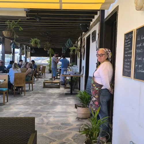 Entrada a la terraza del restaurante Aroma de Sal en Fuerteventura, con una camarera dando la bienvenida y clientes en las mesas.