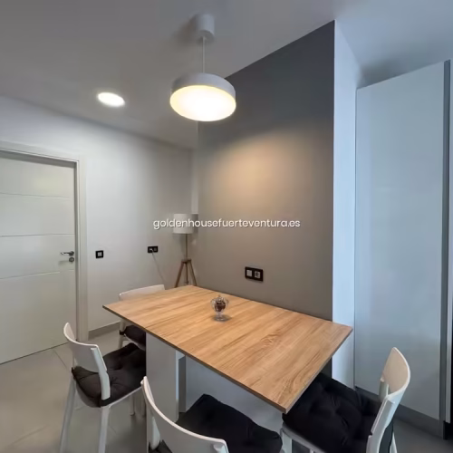 Puerta de entrada blanca junto a la mesa de comedor y lámpara de pie.