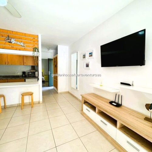 Pasillo de entrada con espejo de pared, perchas de madera y vistas al salón.