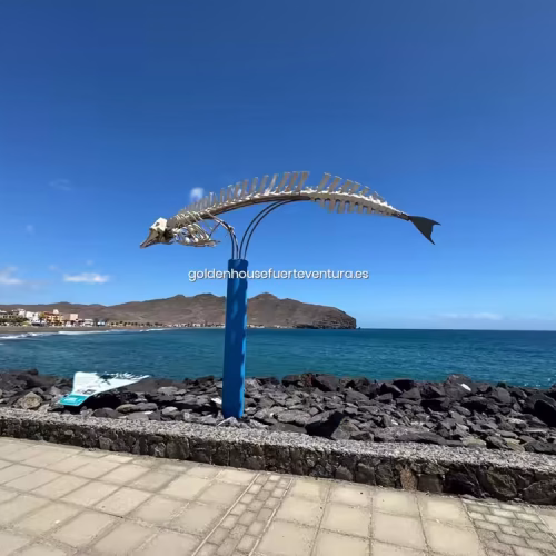 Escultura de esqueleto de ballena frente al mar en el paseo marítimo.
