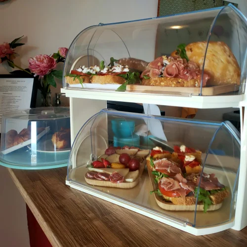Expositores en la barra del restaurante Aroma de Sal mostrando deliciosos pinchos y montaditos recién hechos con jamón, queso y tomate.