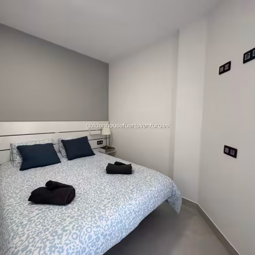 Vista general de habitación doble con suelos de gres y paredes en tono gris suave.