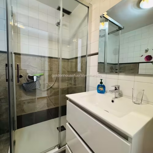 Mueble de baño blanco con lavabo integrado, espejo y jabón de manos.