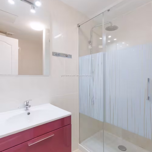 Lavabo moderno con mueble de color rosa y plato de ducha con mampara serigrafiada
