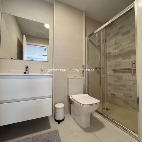Mueble de baño suspendido con cajoneras blancas, espejo grande y plato de ducha.